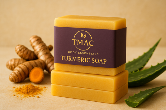 Create a high-resolution lifestyle product mockup of TMAC Body Essentials Turmeric Soap (bar). Show a stack of 2–3 golden-yellow bars wrapped in a purple and gold label featuring the TMAC logo (circle with leaf accent) and the product name “Turmeric Soap”. Place the soaps in a natural lifestyle setting with turmeric roots, turmeric powder, and aloe vera leaves as accents. Lighting should be soft and golden, reflecting a clean, organic, and luxurious skincare aesthetic. Photorealistic style.